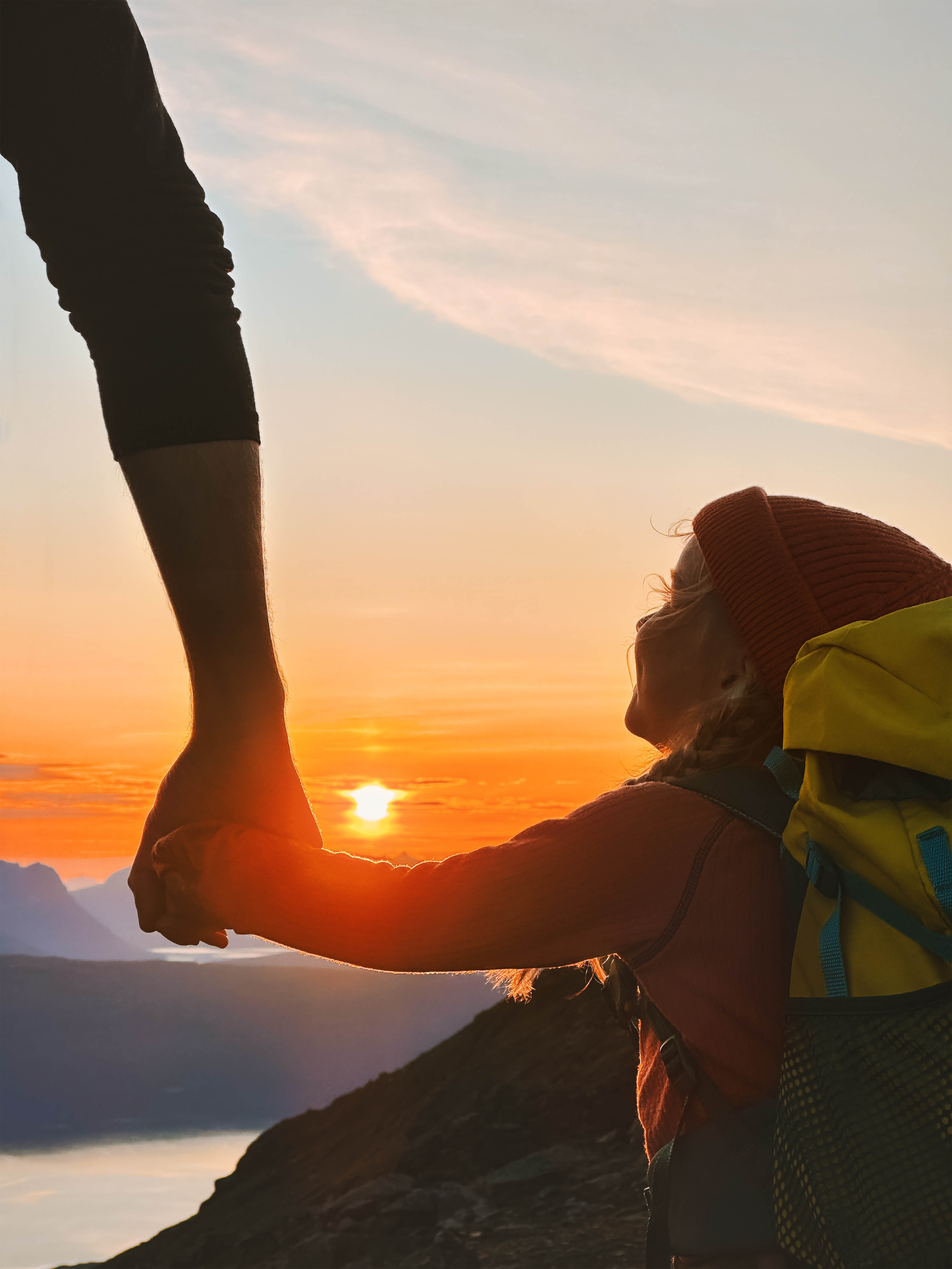 Parent and child holding hands at sunset